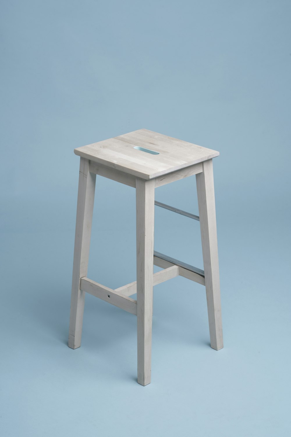 Original pale wooden stool against a blue studio background