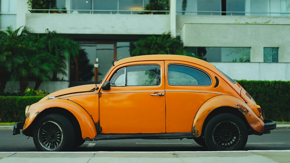 An orange vintage Beetle parked in front of a building, original photo